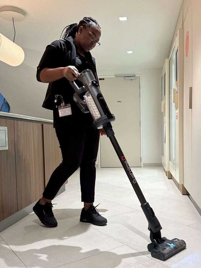 Agent de propreté Syst’aime D en train de nettoyer un espace de bureaux professionnels avec un aspirateur moderne.
